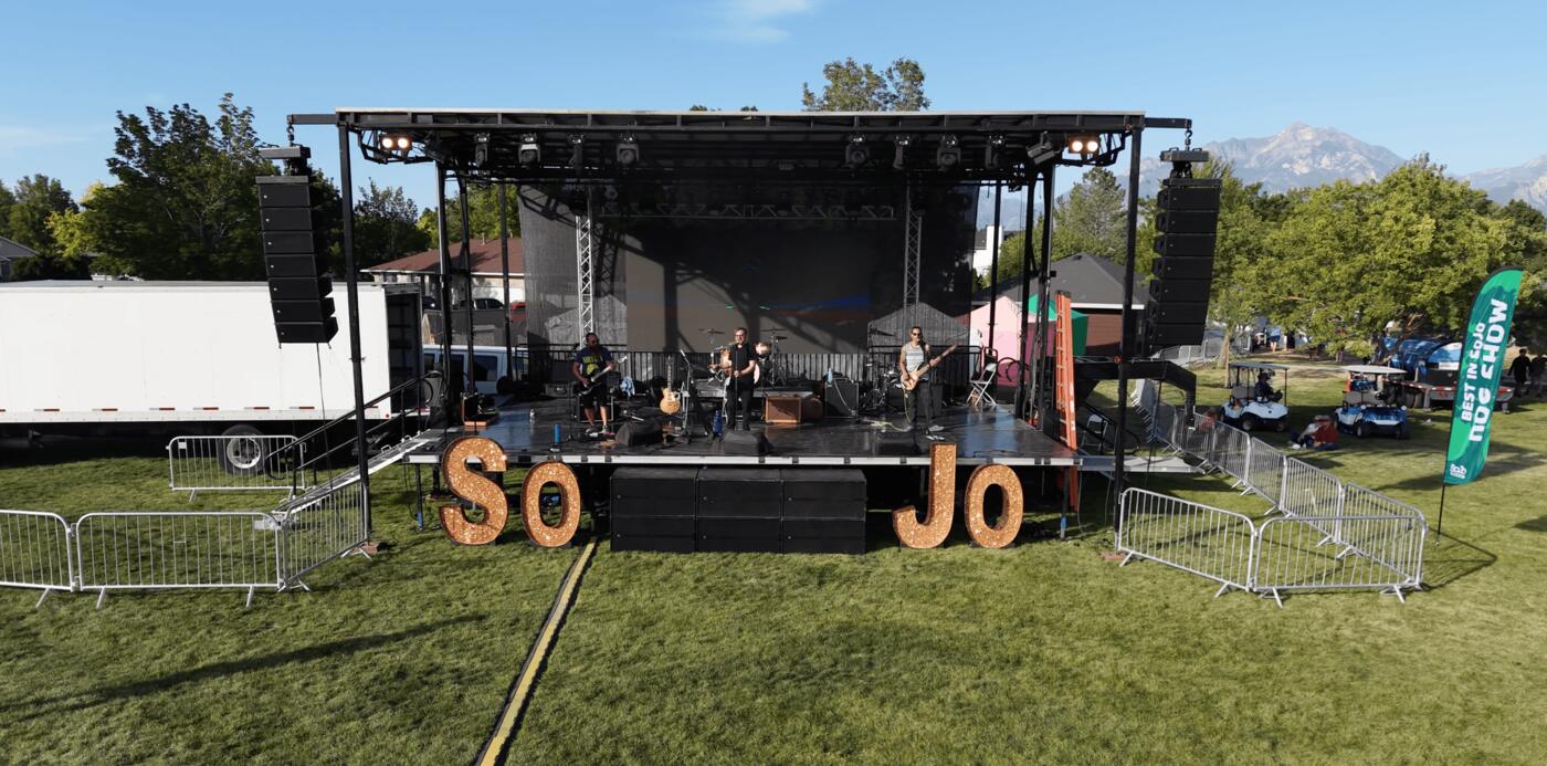 An outdoor civic-event main stage with line arrays and truss