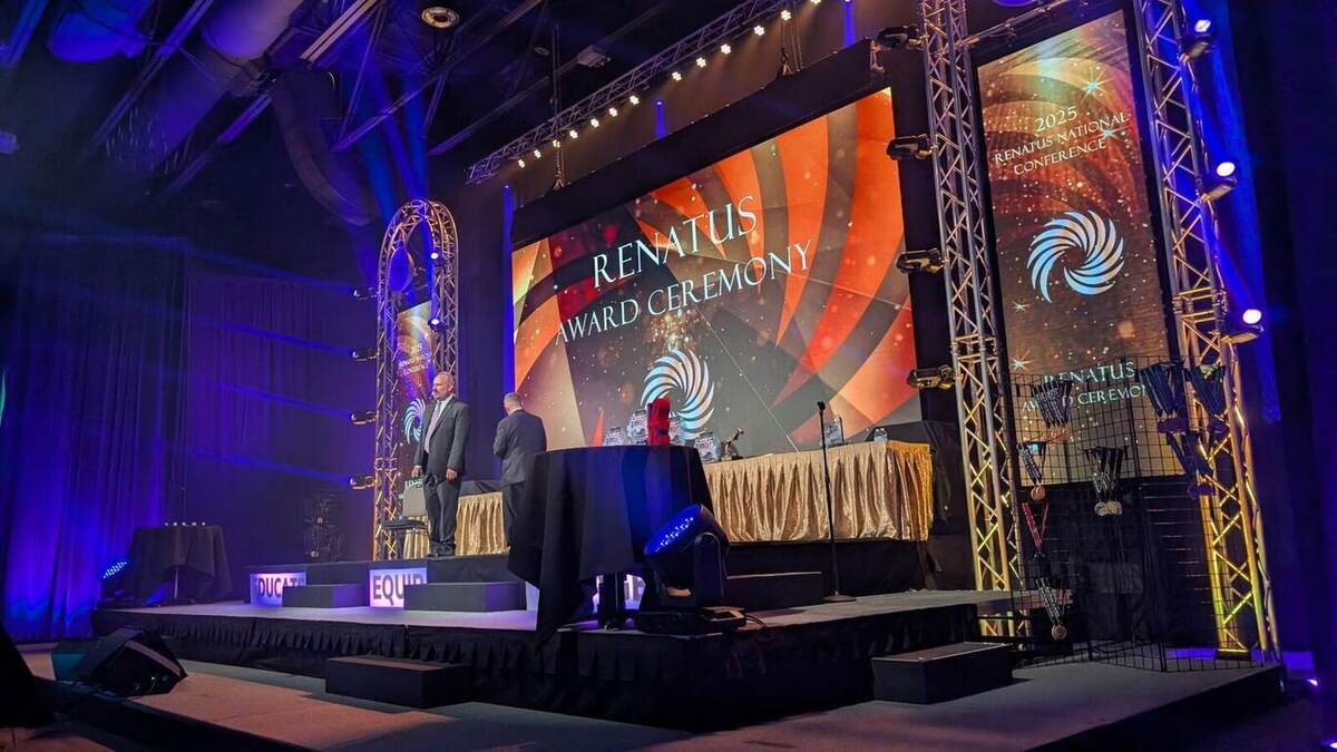 Renatus award ceremony stage with an orange swirl backdrop, gold-draped award tables and medals
