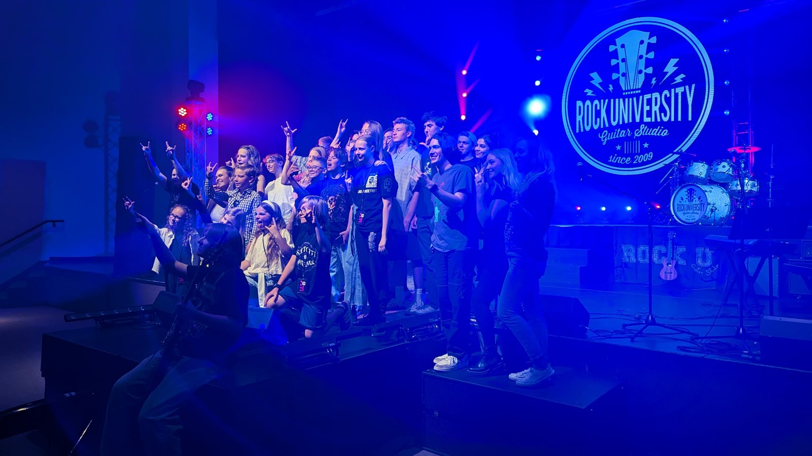 Rock University students together on stage under the branded blue LED wall