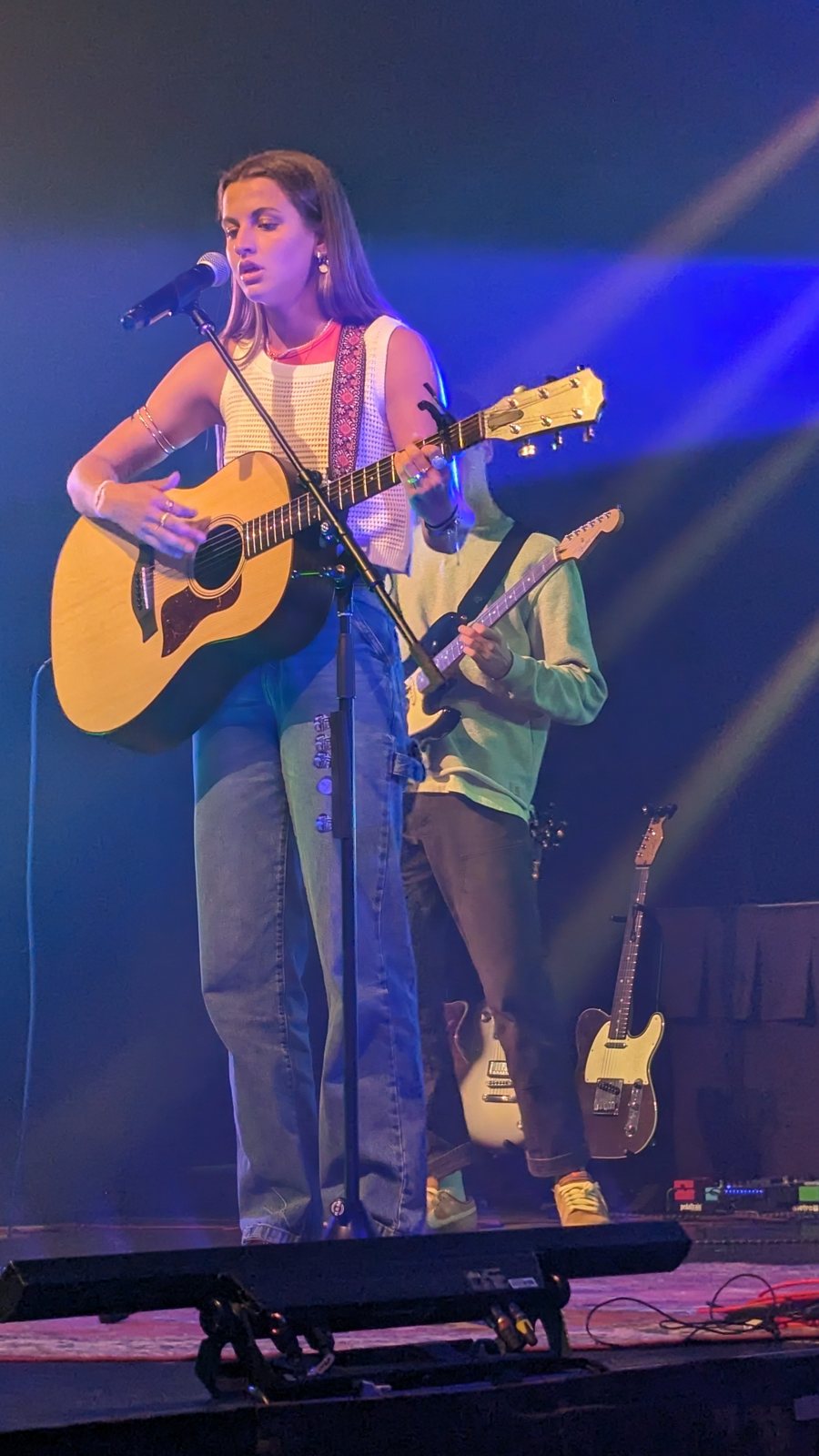 A young guitarist performing solo under concert lighting