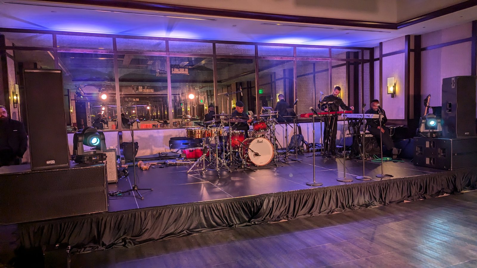 A live band and dance floor at a wedding reception washed in purple light