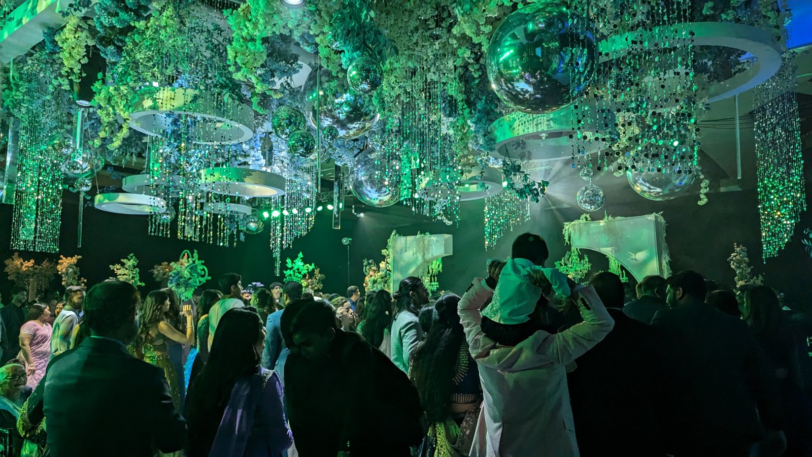 A packed wedding dance floor under color-changing lights