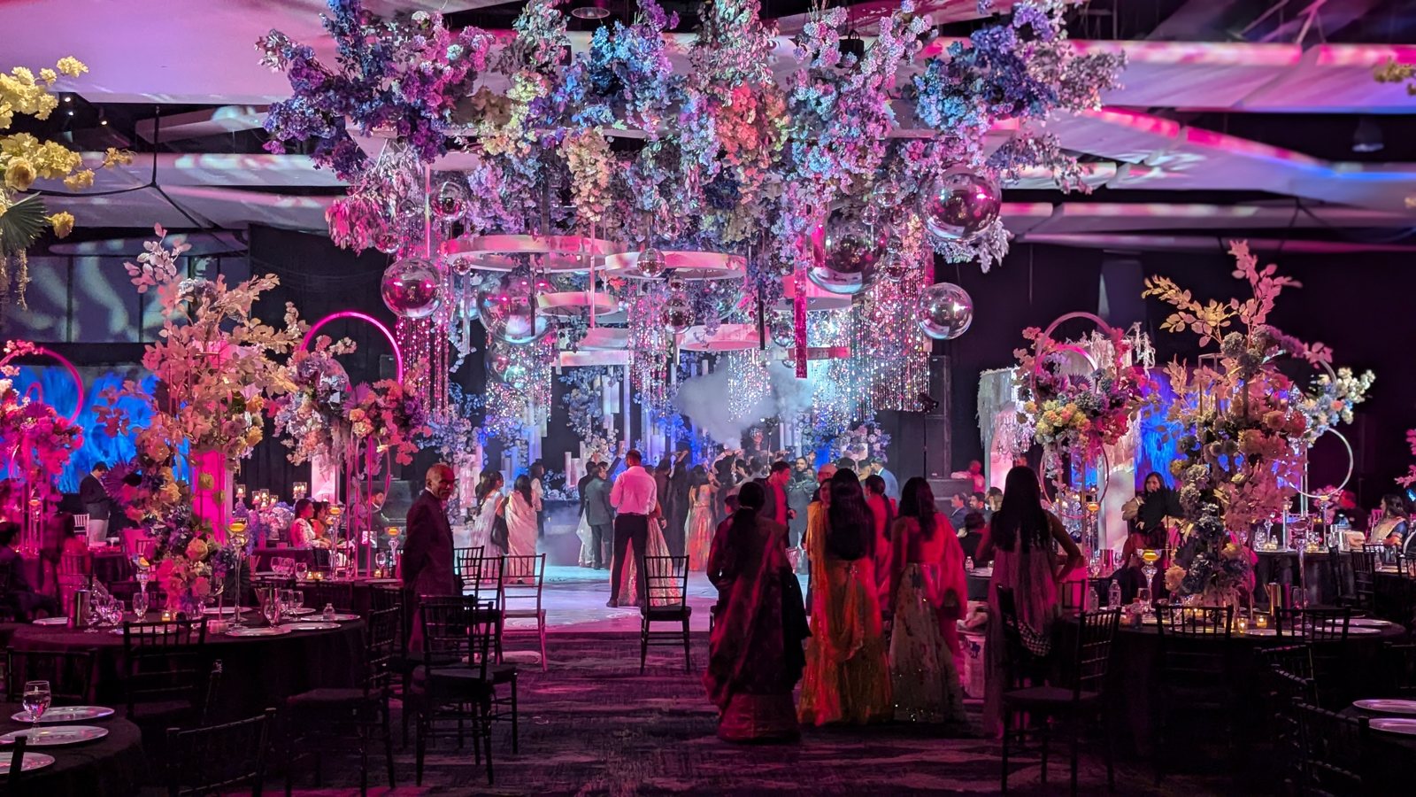 An elegant reception washed in pink and purple uplighting with floral centerpieces